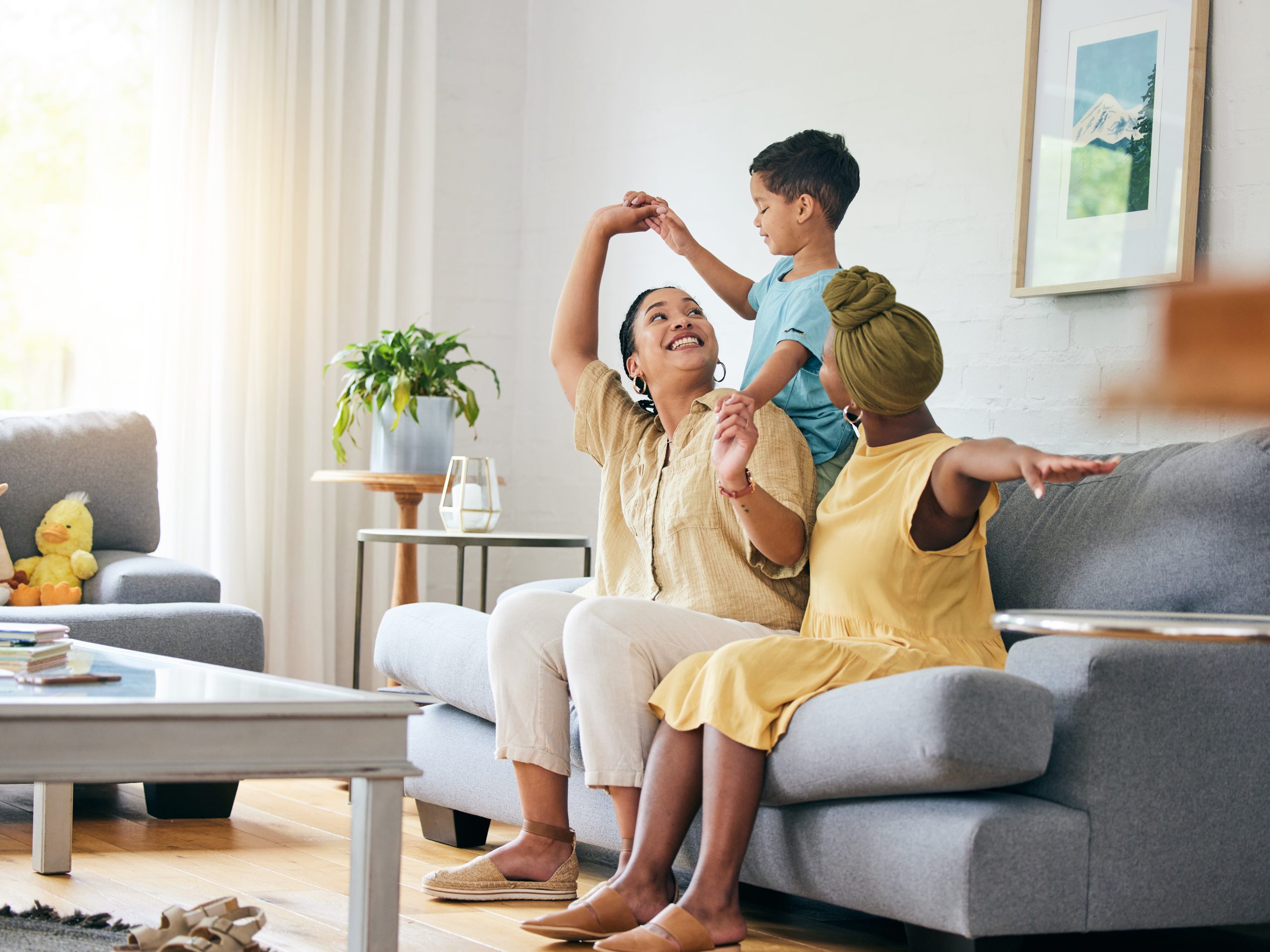 A same sex couple of foster carers playing with their foster child in their living room