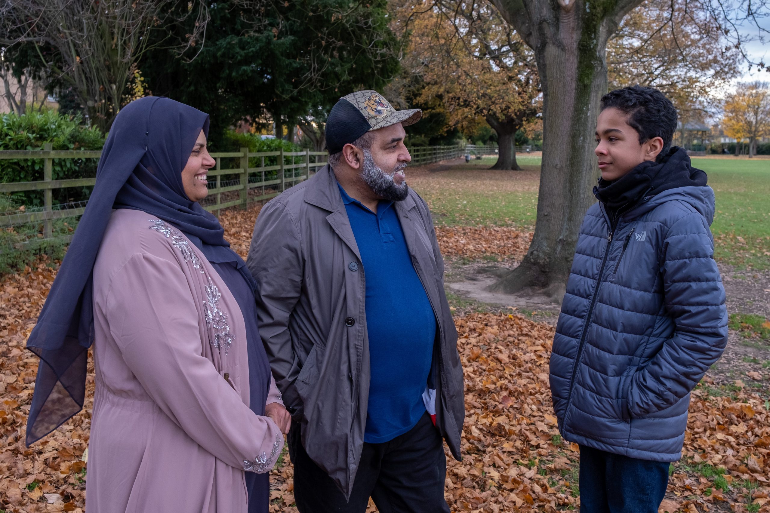 a fostering couple and a young person in a garden talking and smiling with each other
